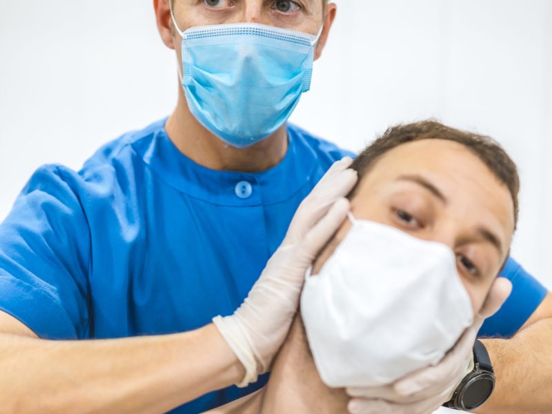 Giving a patient a neck massage. Physiotherapy with protective measures for the Coronavirus pandemic, COVID-19. Osteopathy, therapeutic chiromassage